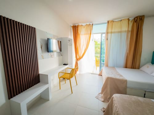 Habitación moderna de La Puerta del Angel con dos camas dobles, TV de pantalla plana, silla amarilla, acceso a balcón y detalles dorados