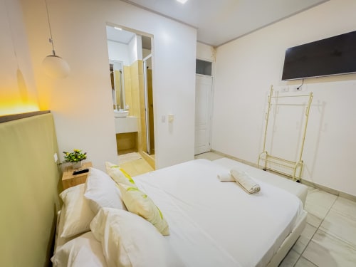 Luminosa habitación moderna en La Puerta del Angel con cama queen, detalles amarillos, baño privado y TV de pantalla plana