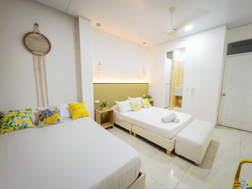 Habitación moderna y luminosa en La Puerta del Angel en Ricaurte con camas gemelas, detalles amarillos y mobiliario contemporáneo