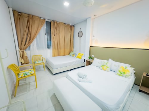 Habitación luminosa en La Puerta del Angel de Ricaurte con dos camas, sillas amarillas y cortinas beige