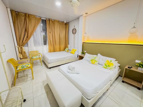 Habitación luminosa de La Puerta del Angel con dos camas, detalles amarillos, cabecera verde y amenidades modernas en Ricaurte