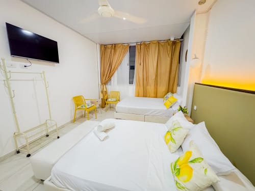Habitación luminosa de La Puerta del Angel con camas gemelas, detalles amarillos, TV y cortinas doradas en Ricaurte, Colombia