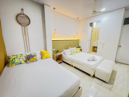 Habitación moderna del hotel La Puerta del Angel con camas gemelas, detalles en amarillo y diseño contemporáneo en Ricaurte, Colombia