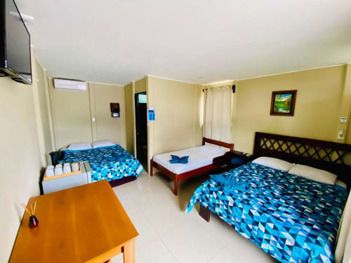 Amplia habitación triple en Cabinas Arenal Home con tres camas, paredes amarillas y comodidades modernas en La Fortuna, Costa Rica