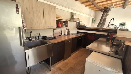Cuisine et salle à manger modernes du gîte Le Mas d'Andiol avec appareils inox et poutres en bois