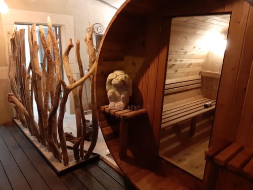 Intérieur de sauna en bois avec décoration de bois flotté et sculpture en pierre au gîte Le Mas d'Andiol