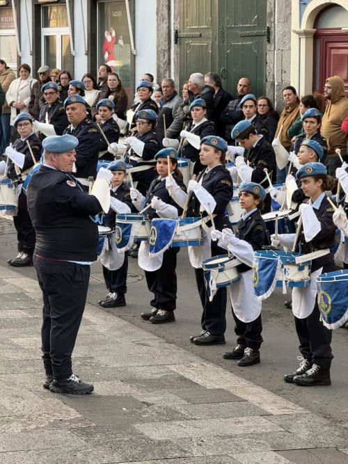Street parade with uniformed youth band in blue berets and white gloves performing in Ribeirinha, Portugal