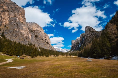 Valle alpina con scarpate ripide, prati verdi e conifere presso Selva di Valgardena