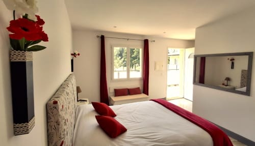 Chambre lumineuse au gîte Le Mas d'Andiol avec lit queen-size, touches rouges, vue sur jardin, miroir et accès au balcon