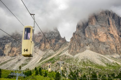 Funivia numero 14 gialla che sale verso i picchi rocciosi drammatici sopra il villaggio alpino di Selva di Val Gardena