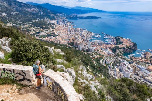 Escursionista che ammira lo skyline costiero di Monaco dal panorama montano vicino agli Rustclea Apartments