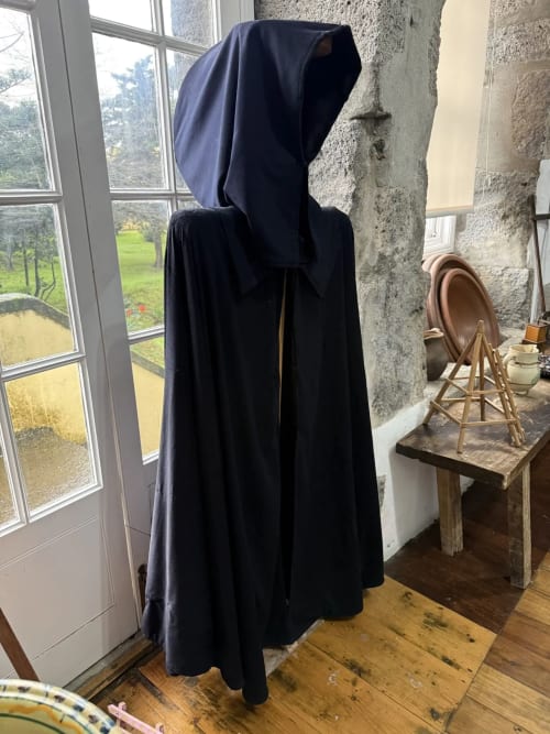 Period costume display at Golden Mermaid Villa, Ribeirinha. Black hooded cloak on mannequin near stone walls and windows.