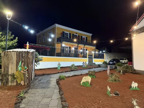 Golden Mermaid Villa in Ribeirinha at night, yellow and white building with decorative cacti and religious statues in front