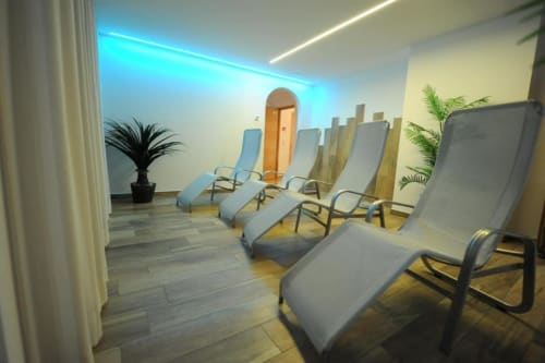 Moderner Entspannungsbereich in den Rustclea Apartments in Selva di Valgardena mit grauen Liegestühlen, Stimmungslicht und Topfpflanzen