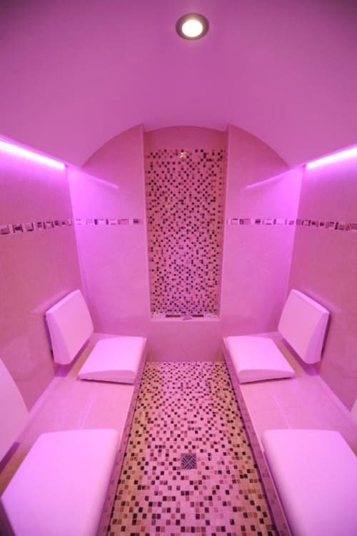 Modern rosa beleuchteter Spa- und Wellnessraum in den Rustclea Apartments in Selva di Valgardena mit Bänken und Mosaikfliesenboden