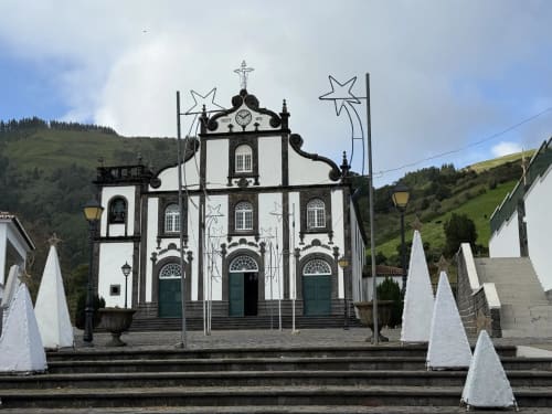 Igreja caiada com detalhes ornamentais pretos em Ribeirinha, Portugal