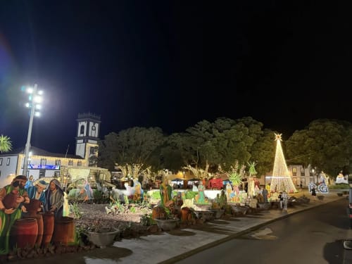 Nighttime Christmas nativity display at Ribeirinha town square with illuminated church, trees, and festive decorations