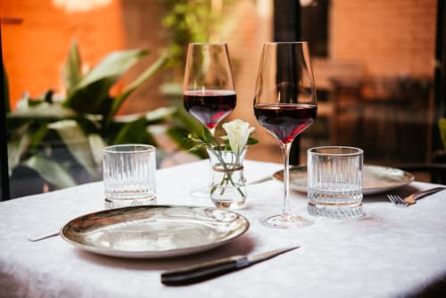 Elegant dining table at Rustclea Apartments with red wine, place settings, and white flowers in Selva di Valgardena.