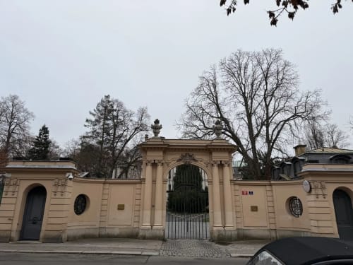 Classical stone gatehouse entrance with green iron gates surrounded by bare trees at Golden Mermaid Villa, Ribeirinha