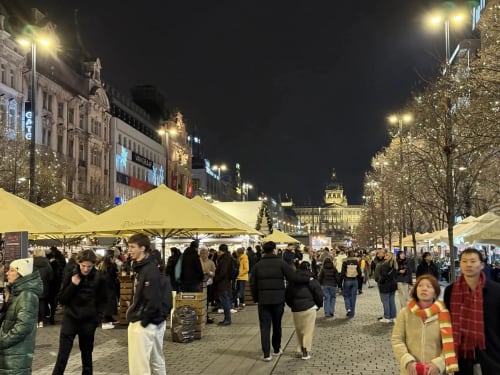 Festive Christmas market with yellow tents and crowds in a European city square at night