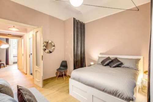 Camera da letto moderna con letto bianco, pavimento in legno e arredamento minimalista presso gli appartamenti Downtown Srl a Roma