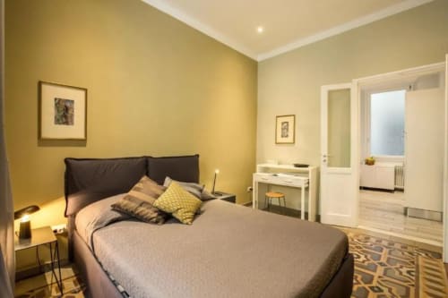 Camera da letto moderna in giallo con letto queen, testata nera, scrivania e specchio in appartamento nel centro di Roma