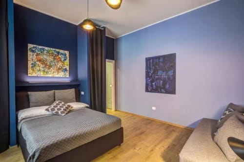 Camera da letto moderna dell'appartamento Downtown Srl Roma con pareti blu, illuminazione a sospensione e pavimenti in legno