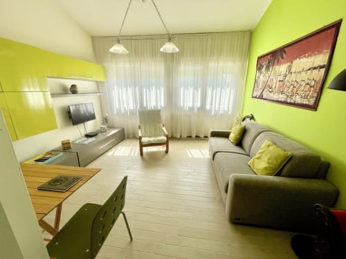 Bright lime green apartment living room at Varenna by Foot with gray sofa, dining area, and mountain view balcony