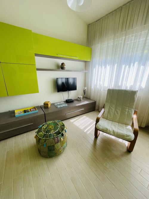 Modern living room at Varenna by Foot with lime green cabinetry, flat-screen TV, comfortable seating, and wooden flooring in