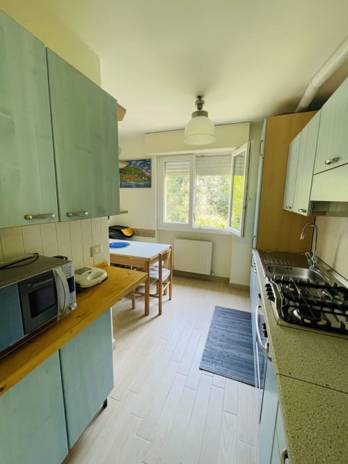 Modern kitchen with mint green cabinets, wooden counters, and dining area at Varenna by Foot apartment