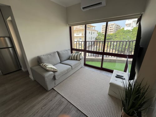 Sala de estar moderna com sofá cinza, varanda com vista para piscina e jardins do Sweet Home Praia Mar, Portimão