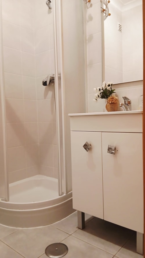 Banheiro moderno com chuveiro, móveis brancos do lavatório e flores decorativas no Sweet Home Paraiso Sol da Rocha
