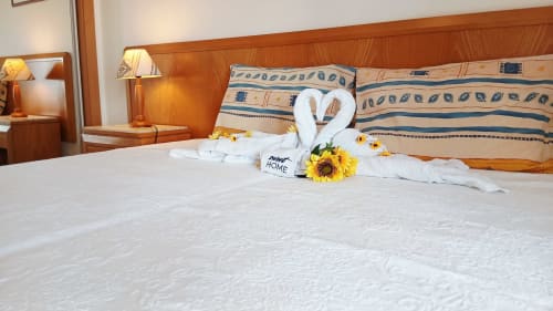 Aconchegante cama de hotel com decoração de cisne em toalha branca, girassóis e placa 'Home' no apartamento Sweet Home em Portimão