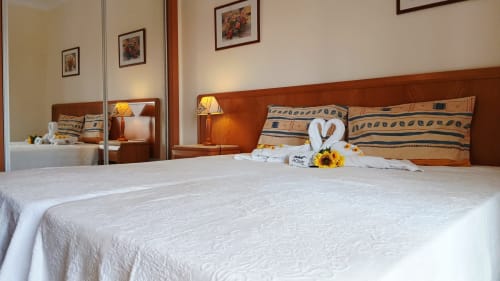 Quarto aconchegante no Sweet Home Paraiso Sol da Rocha em Portimão com roupas de cama brancas, cabeceira de madeira e almofadas decorativas