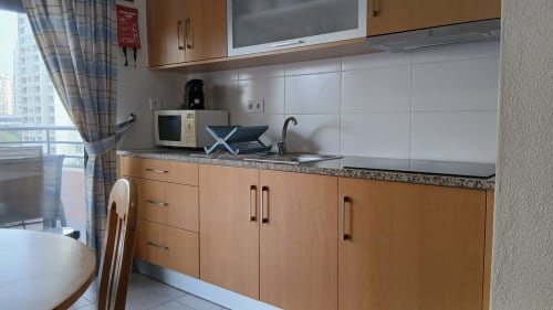 Cozinha moderna do apartamento Sweet Home Portimão com armários de madeira, bancada em granito e vista para a cidade
