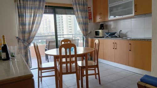 Cozinha-sala de jantar moderna do apartamento Sweet Home em Portimão com vista para a cidade, móveis em madeira e acesso à varanda