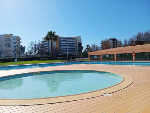 Área de piscinas do Sweet Home Paraiso Sol da Rocha em Portimão com spa circular, piscina olímpica e edifício de instalações em terracota