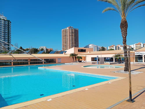 Piscina do apartamento Sweet Home Paraiso Sol da Rocha em Portimão com palmeira e edifícios da cidade