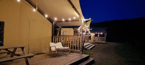 Illuminated glamping lodge with patio seating at Les Cabanes du Nideck, Oberhaslach, at dusk with mountain views