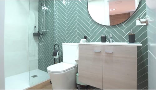 Baño moderno en ML Apartments Valencia con azulejos verde espiga, lavamanos blanco, inodoro y cabina de ducha