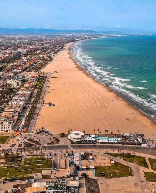 Vista aérea de Playa Las Arenas en Valencia con arena blanca, Mar Mediterráneo turquesa y edificios frente al mar