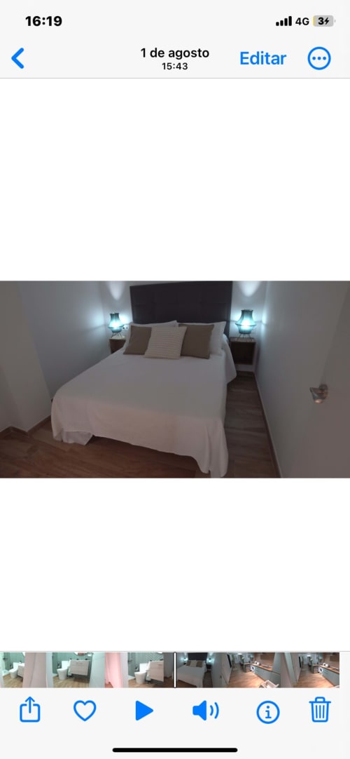 Dormitorio moderno con ropa de cama blanca, cabecero negro y lámparas de noche turquesas en ML Apartments, Valencia