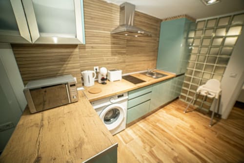 Cocina moderna en ML Apartments Valencia con encimeras de madera, armarios menta, lavadora y electrodomésticos de acero inoxidable