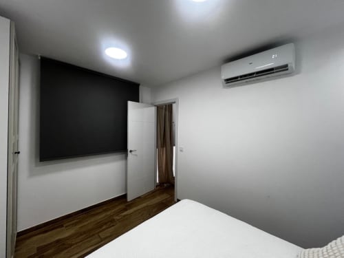 Habitación moderna con aire acondicionado split, televisor de pantalla grande y piso de madera en ML Apartments Valencia