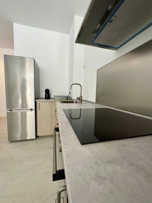 Cocina moderna en ML Apartments Valencia con refrigerador de acero inoxidable, fregadero, encimeras negras y paredes blancas