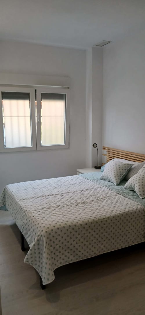 Dormitorio moderno y luminoso en ML Apartments Valencia con cama doble, cabecero de madera, gran ventanal y decoración minimalista