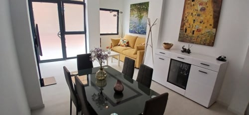 Comedor moderno en ML Apartments Valencia con mesa negra, cocina integrada y sillón amarillo