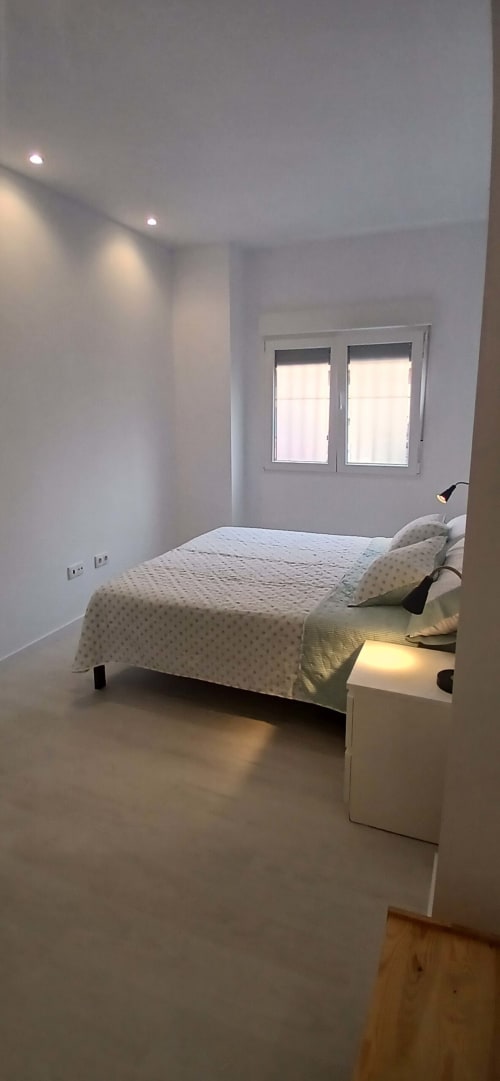 Dormitorio moderno y luminoso en ML Apartments Valencia con cama queen, ropa de cama blanca, grandes ventanales, iluminación empotrada y