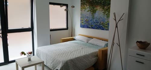 Dormitorio moderno y luminoso en ML Apartments Valencia con cama de madera, arte de nenúfares, ventanales del piso al techo y