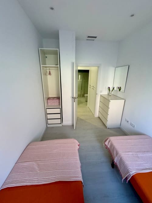 Dormitorio compartido moderno en ML Apartments Valencia con dos camas individuales, armarios blancos, espejo y baño privado